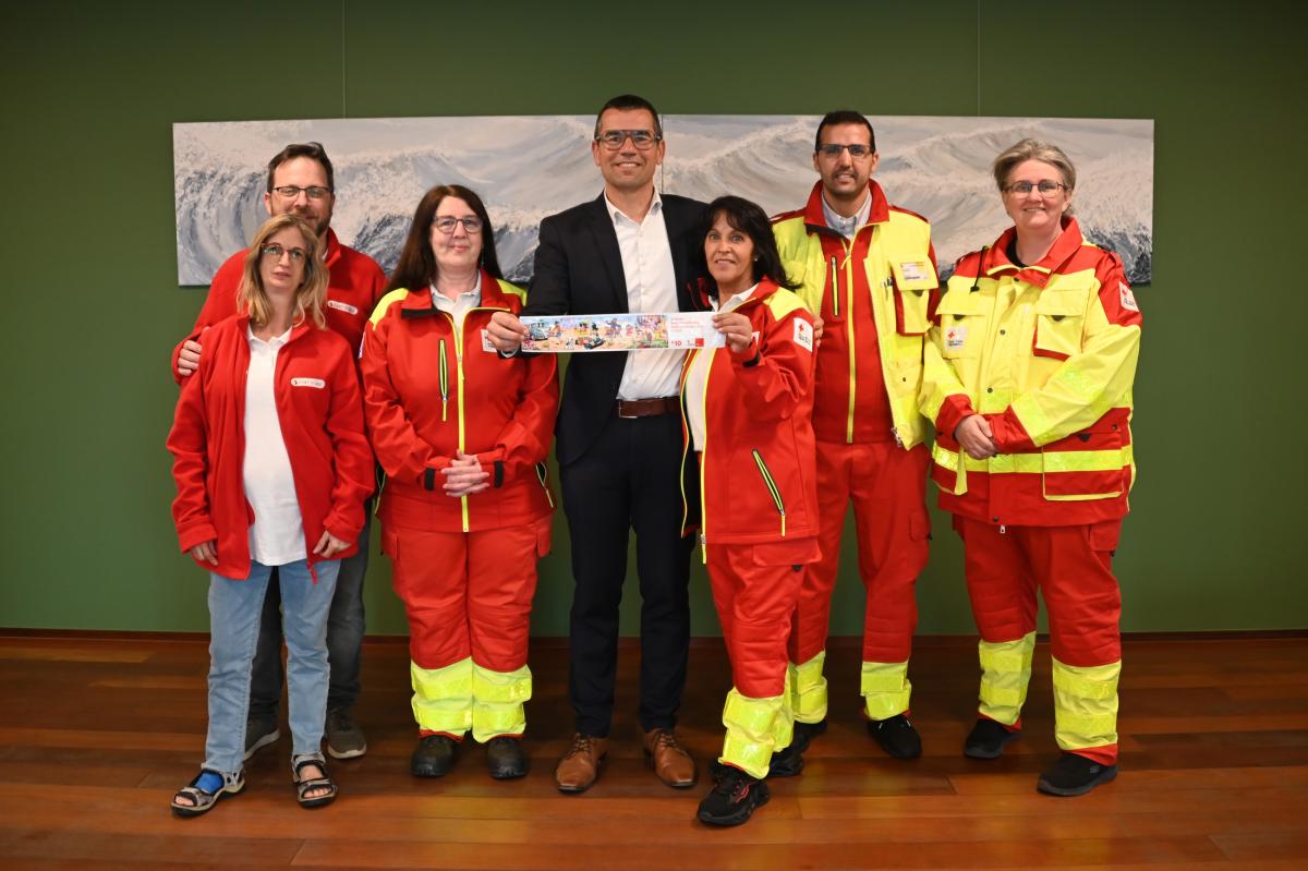 Rode Kruis vrijwilligers en burgemeester Sander Loones met een sticker van het Rode Kruis